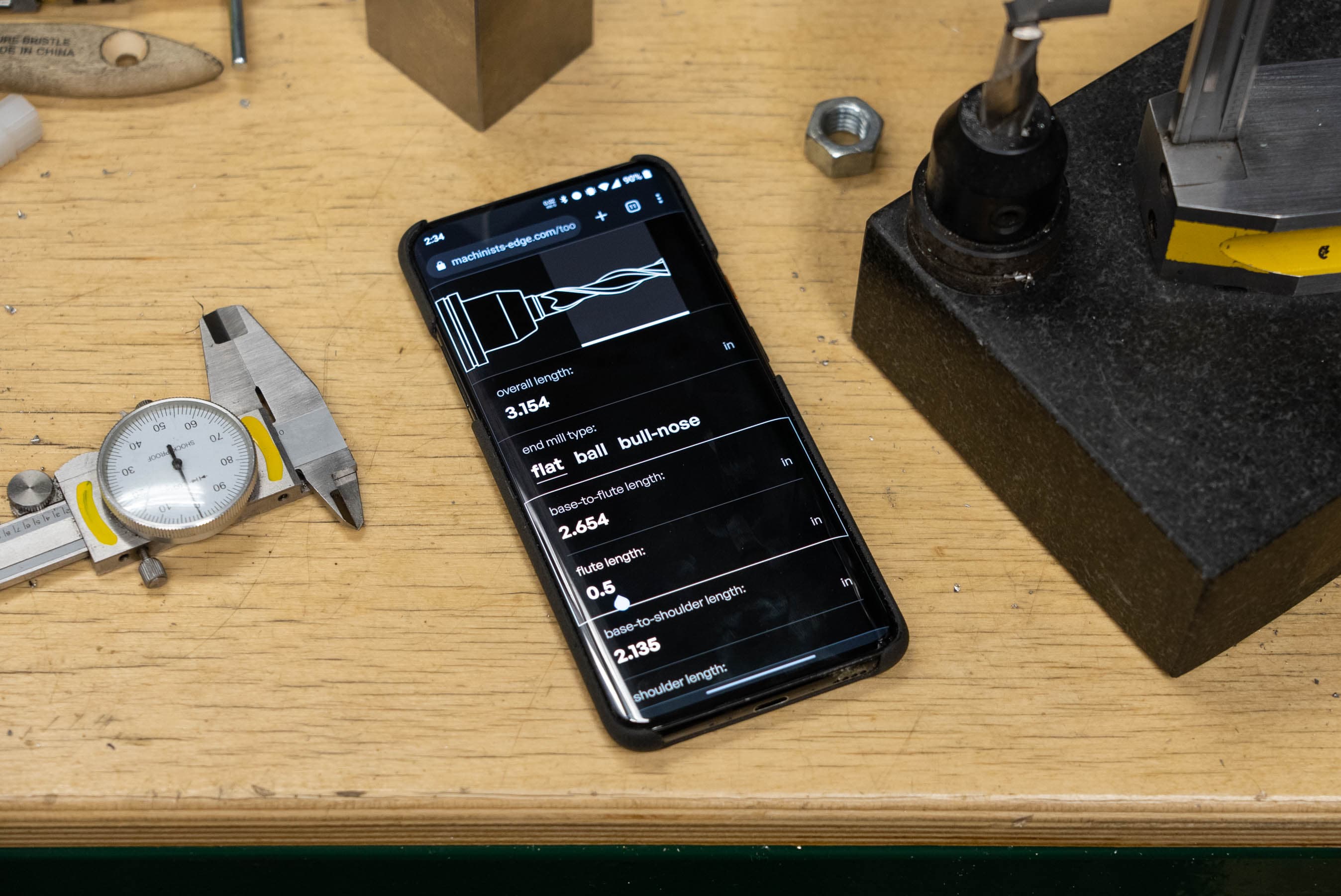 A OnePlus 7T Pro on a workbench displaying the tool length calculator page in dark mode.