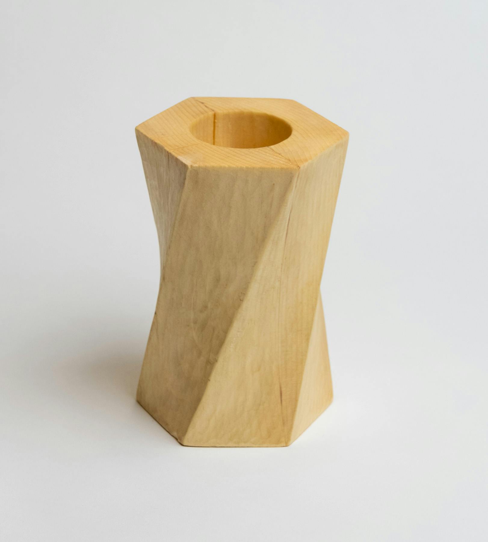 A twisted hexagonal prism made of pine wood with a deep cavity at the top.